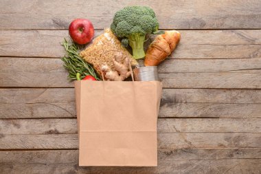 Tahta zemin üzerinde farklı ürünler olan kağıt torba.