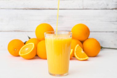 Hafif ahşap zemin üzerinde bir bardak portakal suyu.