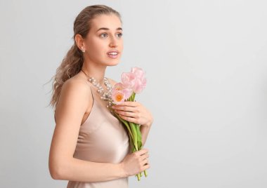 Işıklı arka planda çiçekleri olan güzel genç bir kadın.