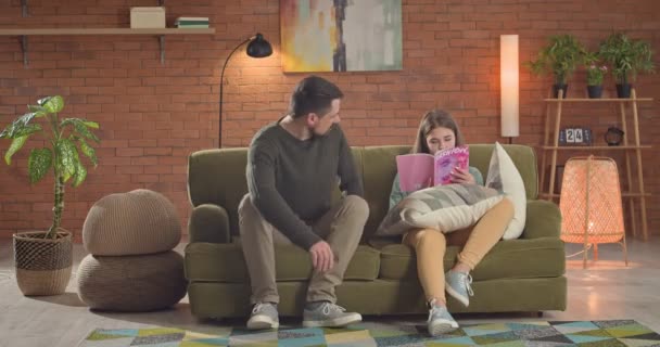 Adolescente Leyendo Revista Negándose Escuchar Padre Mientras Está Sentado Sofá — Vídeo de stock