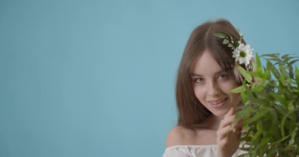 美丽的年轻女子 有着绿色的分枝 背景是彩色的 — 图库视频影像