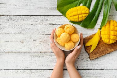 Hafif ahşap arka planda mangolu dondurma yiyen kadın.