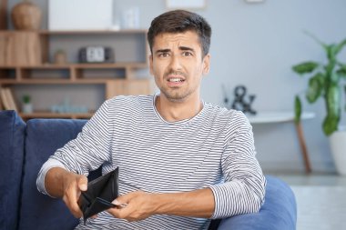 Evde cüzdanı boş üzgün bir adam.