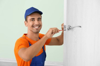 İşçi kapı kilidini tornavidayla onarıyor