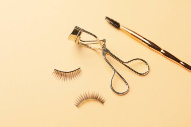Renk arkaplanında bigudi, fırça ve takma kirpikler