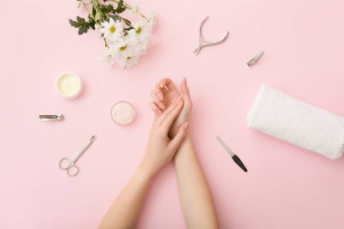 Kadın elleri, manikür malzemeleri ve renkli arka planda güzel çiçekler.