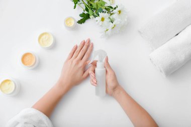 Kozmetik ürünleri olan kadın elleri ve arka planda güzel çiçekler.