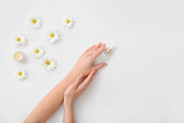 Kozmetik ürünleri olan kadın elleri ve arka planda güzel çiçekler.