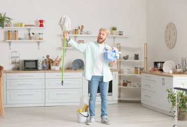 Mutfakta temizlik malzemesi olan genç bir adam.