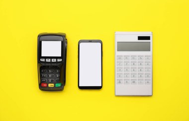 Renk arkaplanında ödeme terminali ve cep telefonu olan hesap makinesi