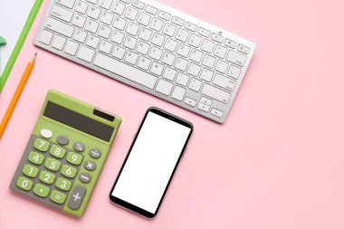 Renk arkaplanında cep telefonu ve bilgisayar klavyesi olan hesap makinesi