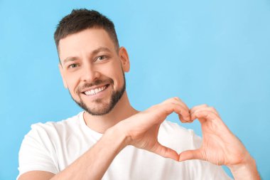 Renkli arka planda elleri olan adam kalp yapıyor.