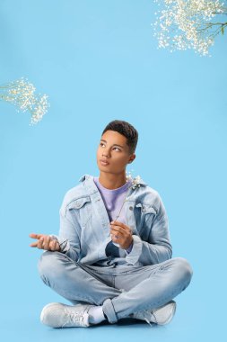 Renkli arka planda çiçekleri olan yakışıklı bir gencin portresi.