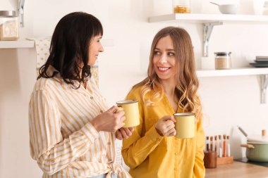 Annesiyle birlikte evde çay içen genç bir kadın.