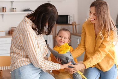 Genç bir kadın ve küçük kızı anneler gününde annelerini karşılıyorlar.