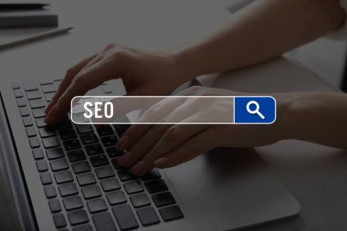 Bilgisayarlı genç bir kadın masada web arama motoru kullanıyor.