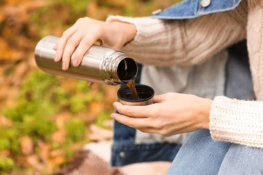 Termoslu genç bir kadın sıcak çay içiyor.