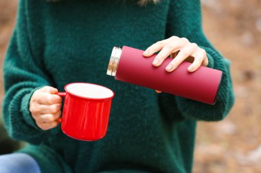 Termoslu kadın turist ormanda sıcak çay içiyor, yakın plan.