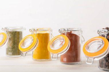 Farklı baharatlı kavanozlar ahşap masada beyaz arka planda