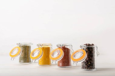 Farklı baharatlı kavanozlar ahşap masada beyaz arka planda