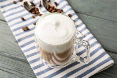 Gri ahşap arka planda bir bardak lezzetli latte.