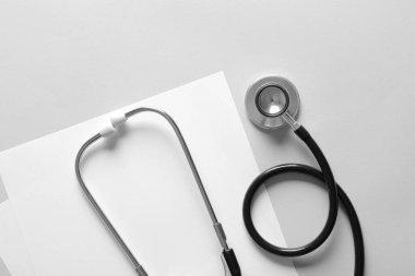 Işık arkaplanı üzerine modern steteskop ve kağıtlar