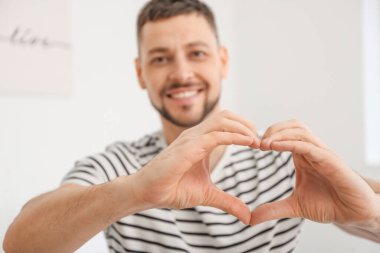 Elleriyle kalp yapan bir adam.