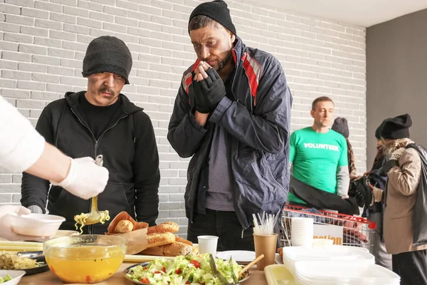 Volunteer giving food to homeless people in warming center