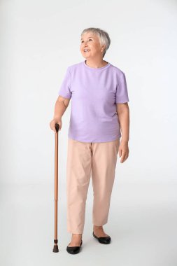 Beyaz arka planda bastonu olan son sınıf öğrencisi bir kadın.