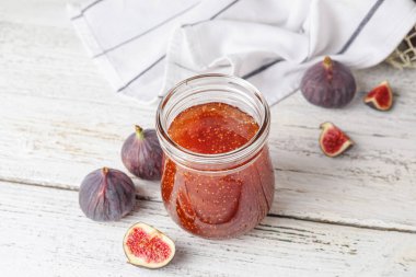 Beyaz ahşap masada incir reçeli kavanozu