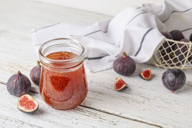 Beyaz ahşap masada incir reçeli kavanozu