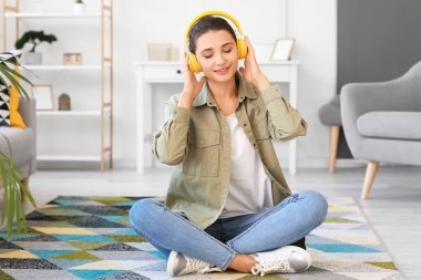 Evde kulaklıklı genç bir kadın var.