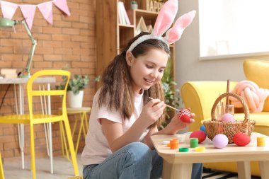 Evde paskalya yumurtası boyayan tatlı bir kız.
