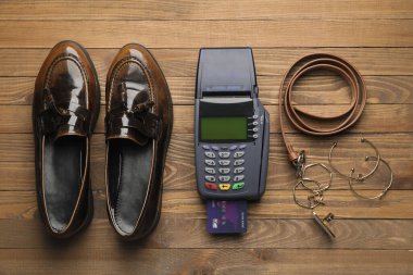 Tahta arka planda kredi kartı, ayakkabı ve aksesuarları olan ödeme terminali