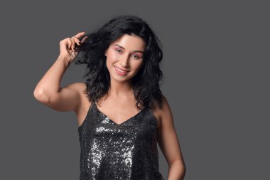 Siyah arka planda güzel kıvırcık saçlı genç bir kadının portresi.