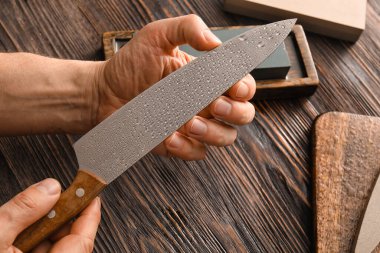 Ahşap arka planda bıçaklı bir erkek, yakın plan.