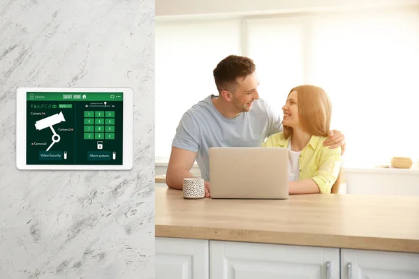 Happy young couple in kitchen under protection of smart home security system