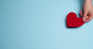 Kadın arka plana kırmızı kağıt kalpler koyuyor