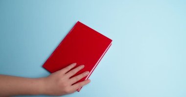 Renkli arka planda kırmızı kağıt kalbi olan kadın kitabı açıyor