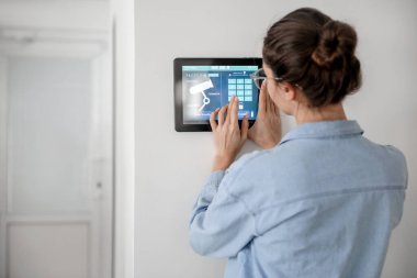 Akıllı ev güvenlik sistemi kontrol paneli kullanan kadın