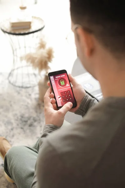 Man with mobile phone using smart home security system application