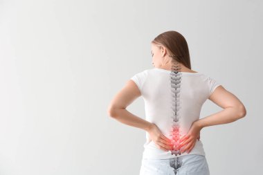 Arka planda sırt ağrısı çeken genç bir kadın.