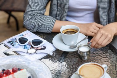 Kaliteli kol saati olan bir kadın kafede kahve içiyor.