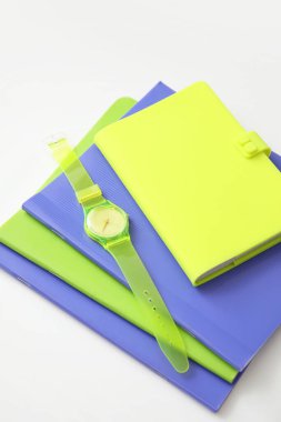 Hafif arkaplanda not defterleri olan şık bir kol saati