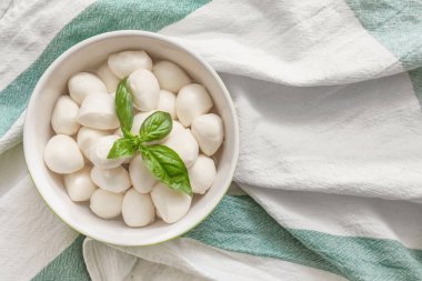 Kumaş zemin üzerinde mozzarella peyniri olan bir kase