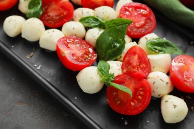 Koyu arka planda mozarella peyniri, domates ve fesleğen, yakın plan.