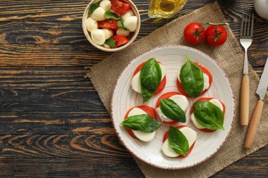 Ahşap arka planda mozzarella peyniri, domates ve fesleğen kompozisyonu