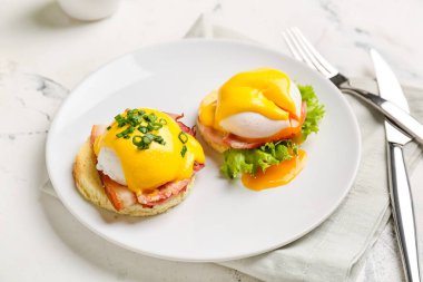 Hafif arka planda lezzetli yumurtalı Benedict tabağı.