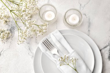 Yanan mumlar ve ışık arka planında çiçek dekoru olan güzel bir masa.