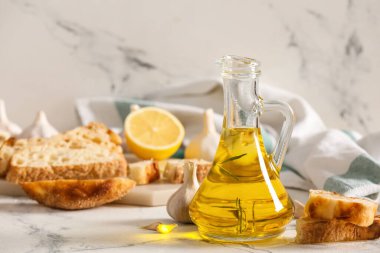 Hafif arkaplanda bir sürahi yağ, ekmek ve sarımsak